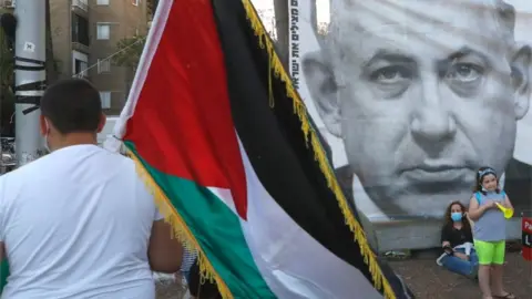 AFP Demonstrator carries a Palestinian flag at a protest in Tel Aviv against Israel's annexation plans (06/06/20)