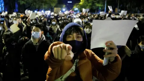 Reuters People hold white sheets of paper in protest over coronavirus disease (COVID-19) restrictions, after a vigil for the victims of a fire in Urumqi, as outbreaks of COVID-19 continue, in Beijing, China, November 27, 2022.