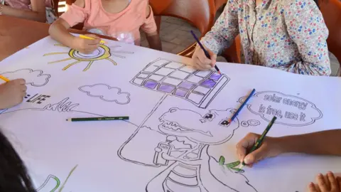 Green Society Children paint a poster encouraging the use of solar energy.