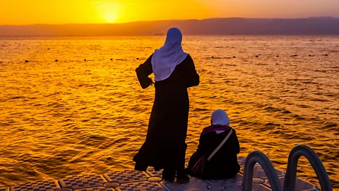 Alamy Jordanian women watch the sunset at the Gulf of Aqaba, Red Sea, Jordan (Credit: Alamy)