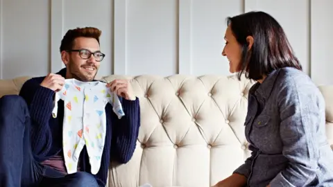 Getty Images Couple looking at baby clothes
