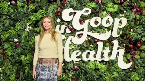 Getty Images Gwyneth Paltrow stands in front of a wall of vegetables