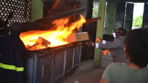 Uganda Revenue Authority Man throwing a box into a fire