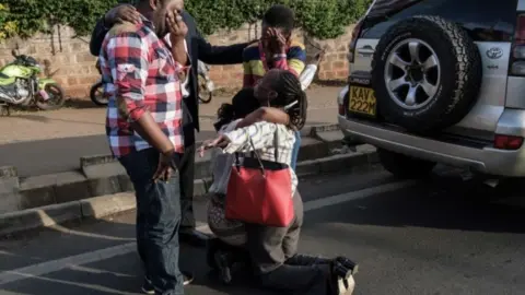 AFP A woman (center lower left) evacuated from DusitD2 compound in Nairobi after a blast followed by a gun battle is reunited with her family on January 15, 2019.
