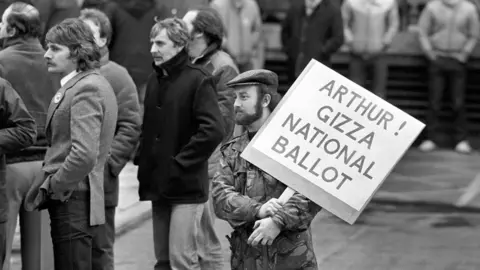 PA A Leicester miner from the Power Group holds a placard addressed to National Union of Miners President Arthur Scargill, outside the NUM"s Sheffield headquarters when Scargill spoke to the Leicester miners.