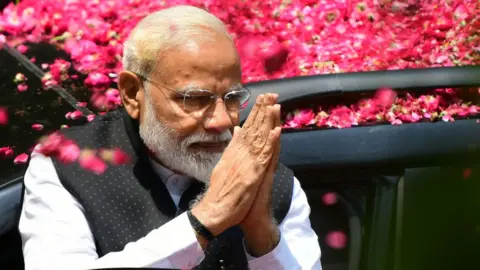 Getty Images Indian Prime Minister Narendra Modi greets supporters as he arrives to file his election nomination papers in Varanasi.