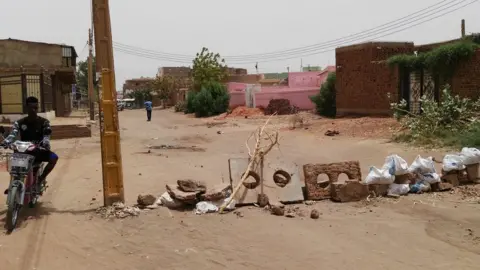 AFP A man on a bike navigates around a makeshift roadblock made up of sticks and blocks of concrete