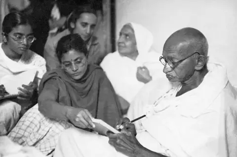 dinodia Gandhi dictating a message with help from Abha and Manu (far left) shortly after breaking his fast. Birla House. New Delhi. India. January 18, 1948