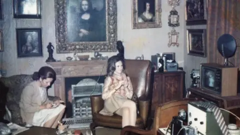 Gilbert family Two women sit beneath a Mona Lisa painting hanging above the fireplace of a 1960s London flat
