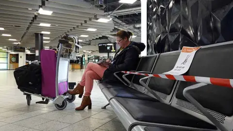 Getty Images People wait to check-in at London Luton Airport as WizzAir starts to resume passenger flights on 1 May