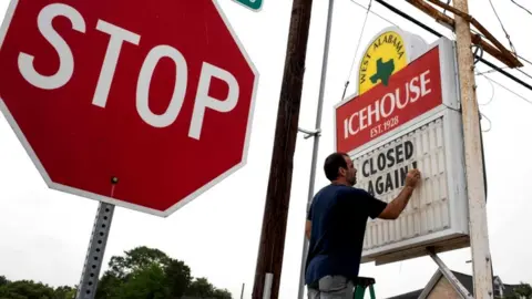 Getty Images Bar owner Petros Markantonis changes the marquee outside his bar to "Closed Again" at the West Alabama Ice House in Houston, Texas, 26 June 2020