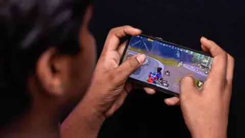 Getty Images A young man in New Delhi playing a computer game on his mobile phone