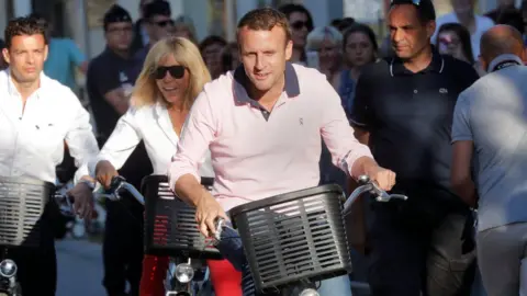 Reuters Emmanuel Macron and his wife, Brigitte Trogneux, riding bikes near their home on Saturday