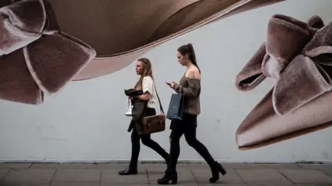 Getty Images Two women walk past a large board advertising shoes on Oxford Street in London on April 28, 2017
