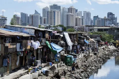 Getty Images Residents of a Manila slum, pictured in front of the city's financial district