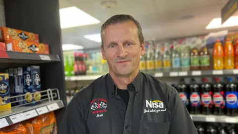 Kate Bradbrook/BBC Matthew Croft with short brown hair standing in his shop