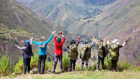 Evolution Treks Peru Women porters, guides and hikers linking arms and looking out on an Inca Trail view