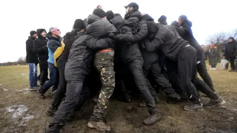 Getty Images Two teams of the Alpha Men Assemble group interlock arms and work together to offer peaceful resistance against each other on January 8, 2022 in Brownhills, England.