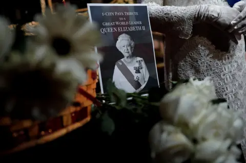 Reuters A note and a bouquet of flowers are pictured next to a wax model of Queen Elizabeth II at a wax museum in Shah Alam, Malaysia September 9, 2022.