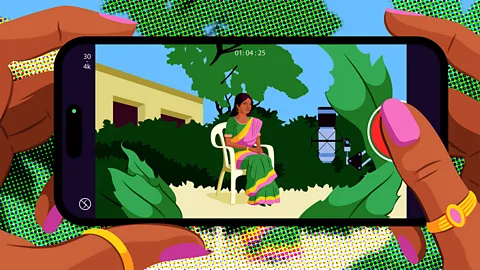 Estudio Santa Rita A brightly coloured illustration of a woman's hands holding a smartphone, which shows a woman wearing a green, pink and yellow sari sat on a white chair surrounded by greenery on the screen (Credit: Estudio Santa Rita)