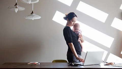 Getty A mum working and holding her baby