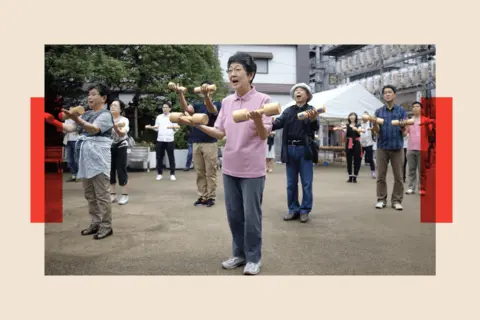 AFP via Getty Images Elderly people work out with wooden dumb-bells in the grounds of a temple in Tokyo