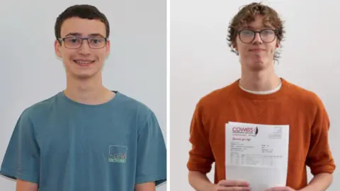 Cowes Sixth Form A composite image of Alfie on the left and Blake on the right, they are both looking at the camera and smiling. Alfie has short dark brown hair and wears thing wired framed blue glasses. He is wearing a light blue short sleeved t shirt with a square logo which has black illustrated ocean waves on his chest. Black has mid length dark blonde hair and wears round black glasses. He is holding his results paper in front of his chest and wears an orange long sleeved wool jumper, with the sleeves ruched up to his elbows.